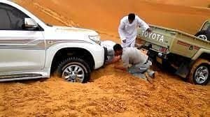 Pick-up truck stuck in soft desert sand being recovered